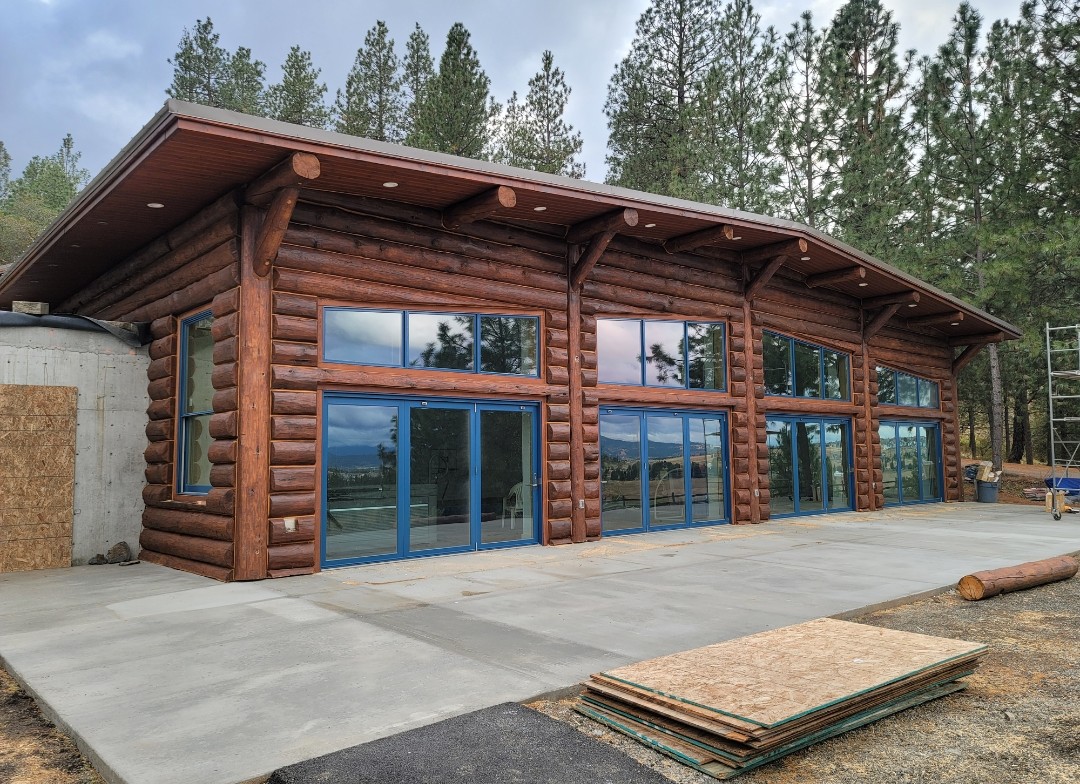 Completed log home with dark stain and blue window frames